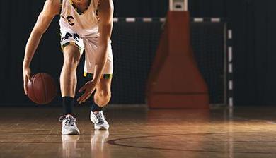 image of a basketball player from the neck down crouched 和 dribbling.